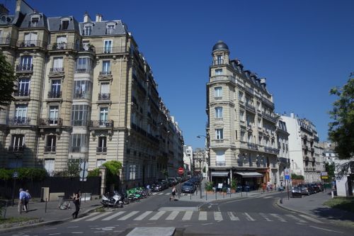 Free Street view of classic Parisian architecture on a sunny day with pedestrians and cafe ambiance. Stock Photo