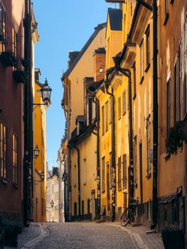 Charming street with yellow buildings in Stockholm's medieval old town, bathed in warm sunlight.
