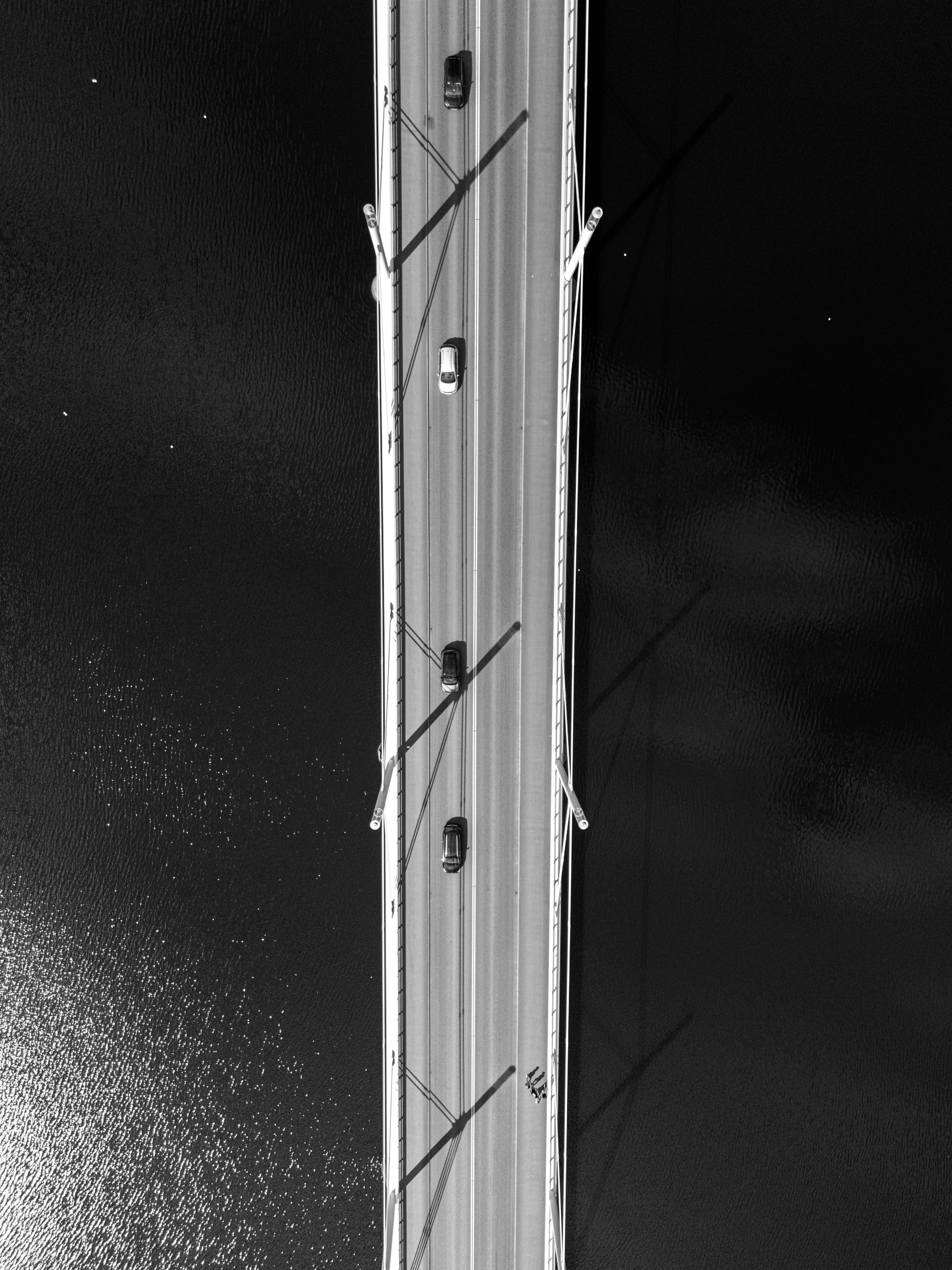 Gratis Vista aérea de coches en un puente sobre un río oscuro, en blanco y negro. Foto de stock