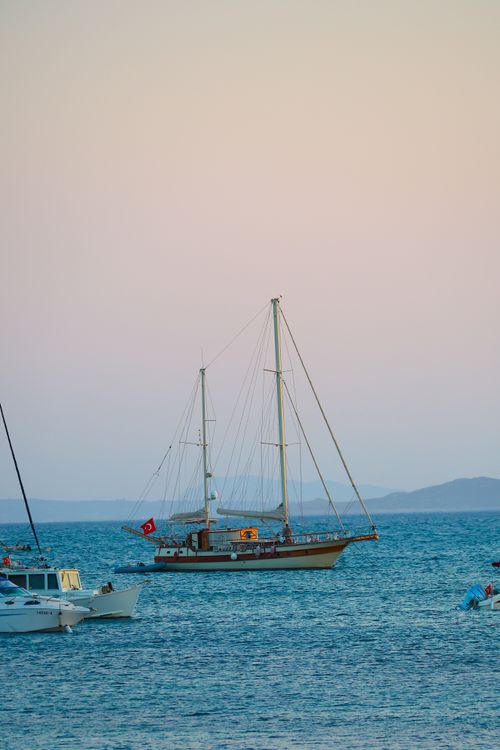 Free A sailboat anchored in tranquil waters at sunset, offering a serene maritime scene. Stock Photo