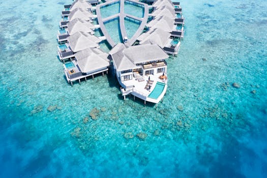 Drone shot of luxury overwater resort villas surrounded by turquoise waters.