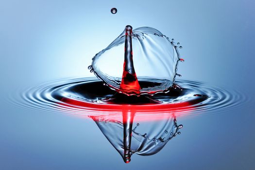 Striking macro photo of a water droplet splash with a red tint, showcasing serene dynamics.