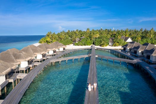 Aerial shot of a luxurious overwater resort on a tropical island with clear blue waters.
