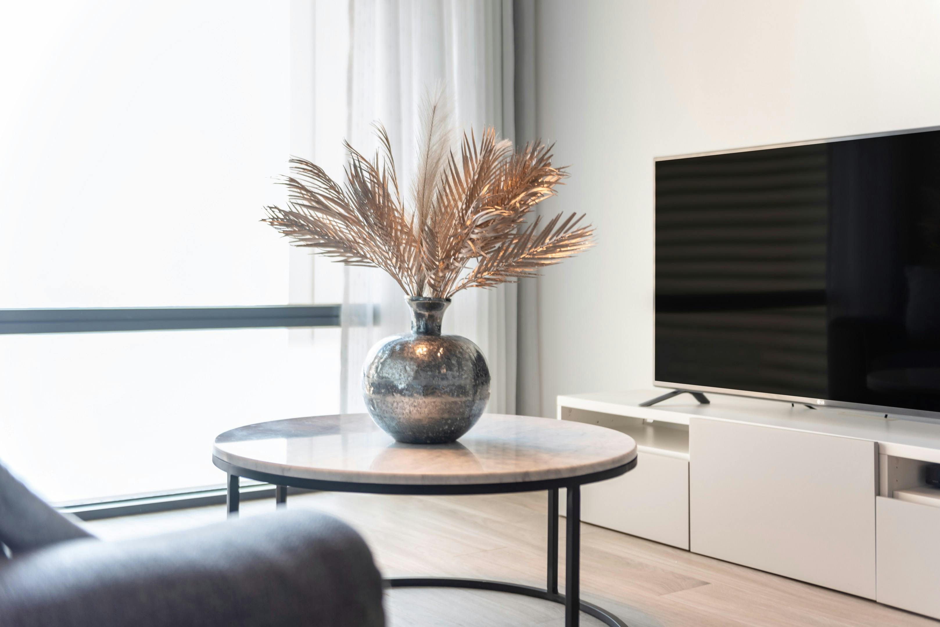 Stylish living room featuring a TV, table, and a vase with decorative leaves.