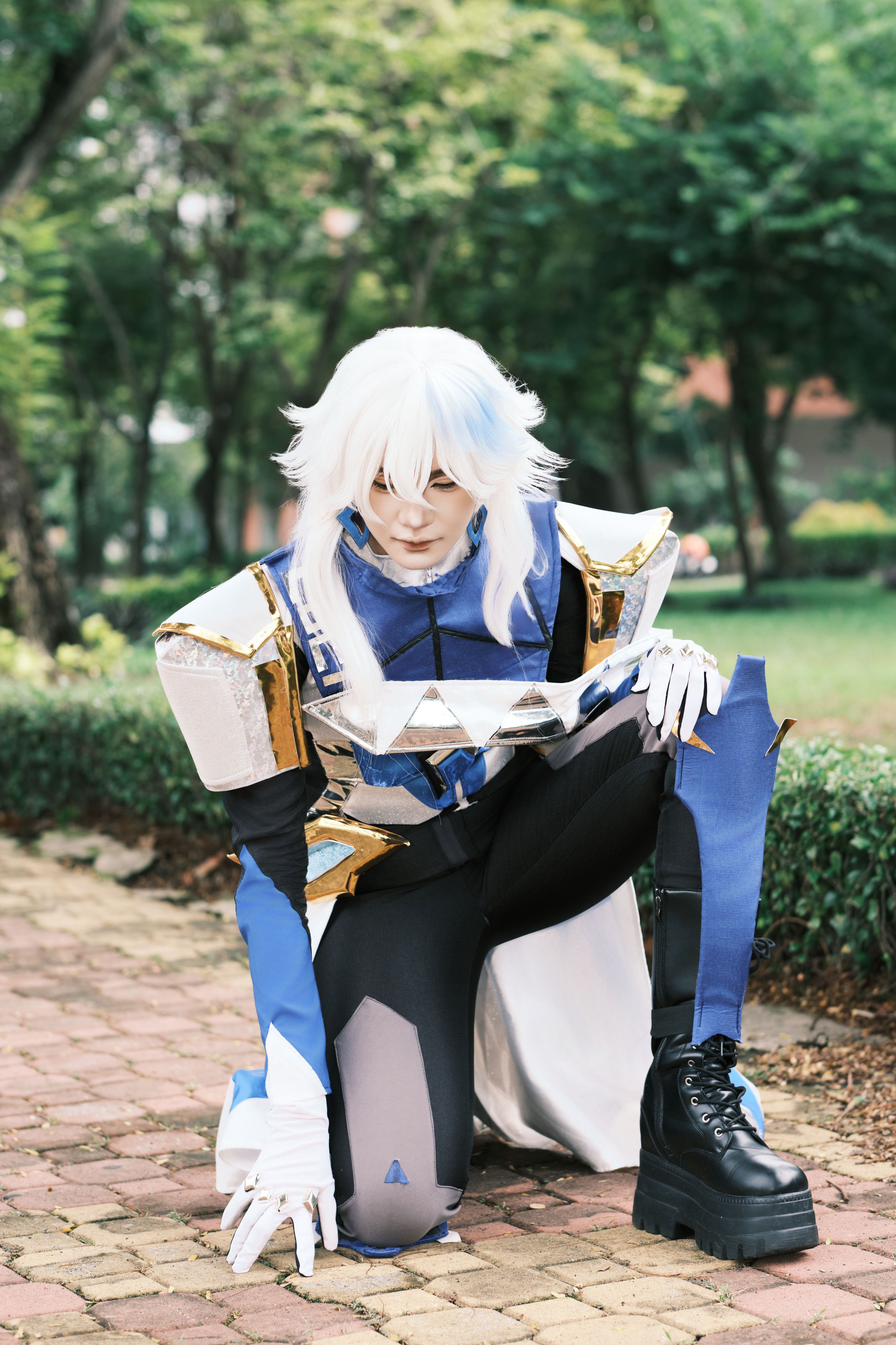 A cosplayer in detailed futuristic armor poses in a park, showcasing intricate costume design.