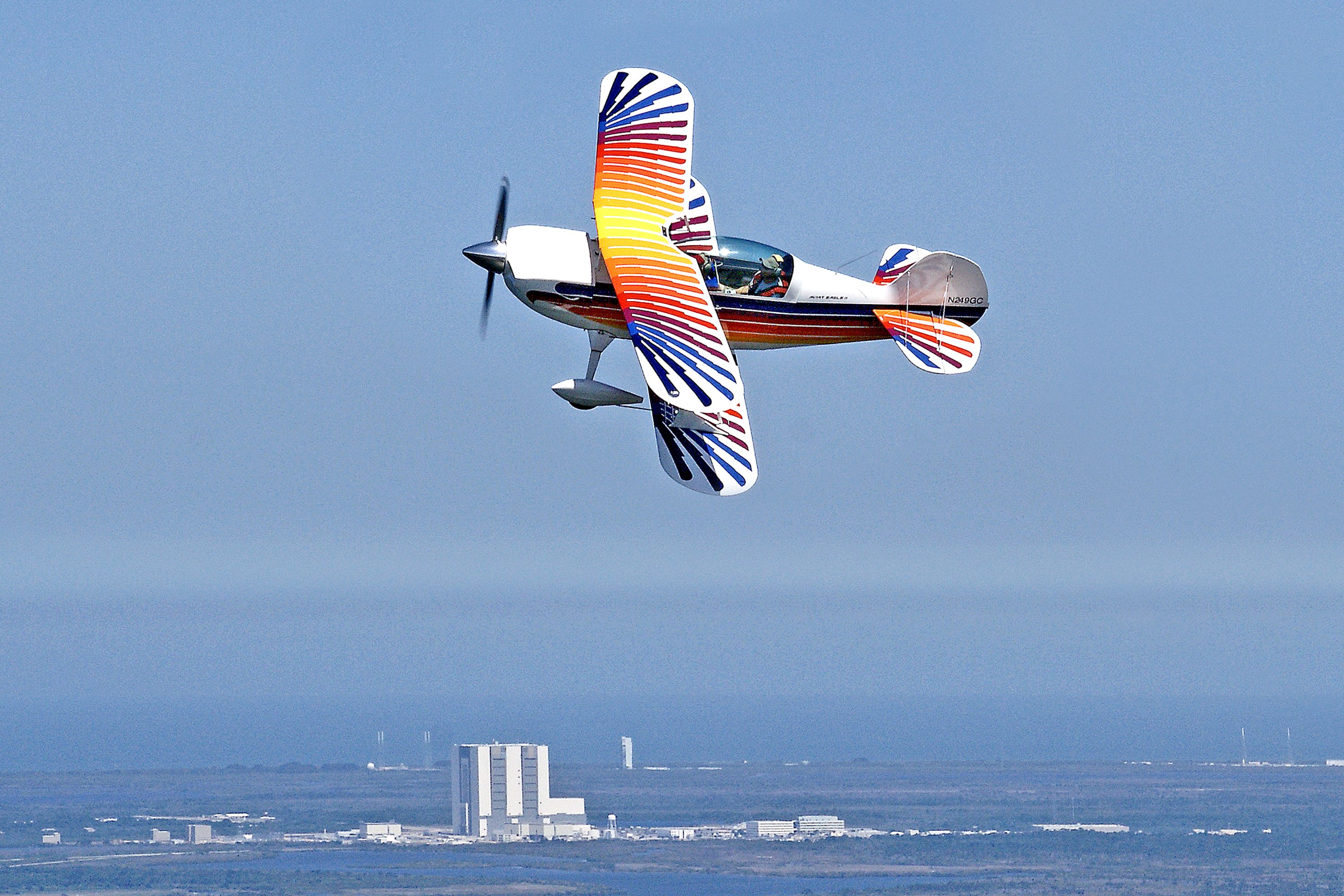 A colorful Christen Eagle bi-plane performs acrobatics above Kennedy Space Center, Florida.