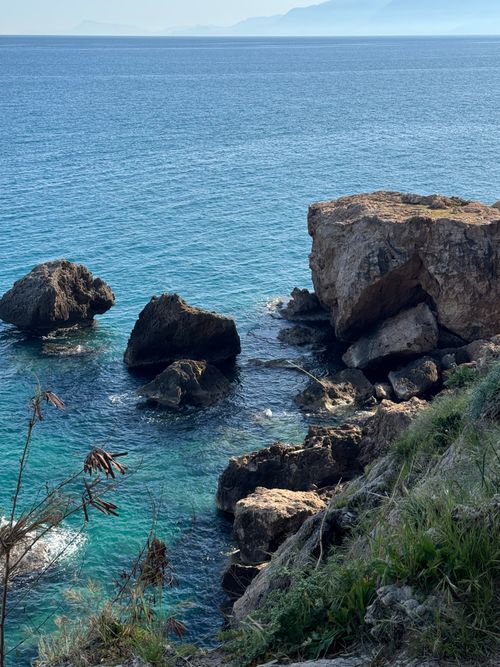 Free Dramatic rocky coastline with crystal clear turquoise waters and lush greenery near the sea. Stock Photo