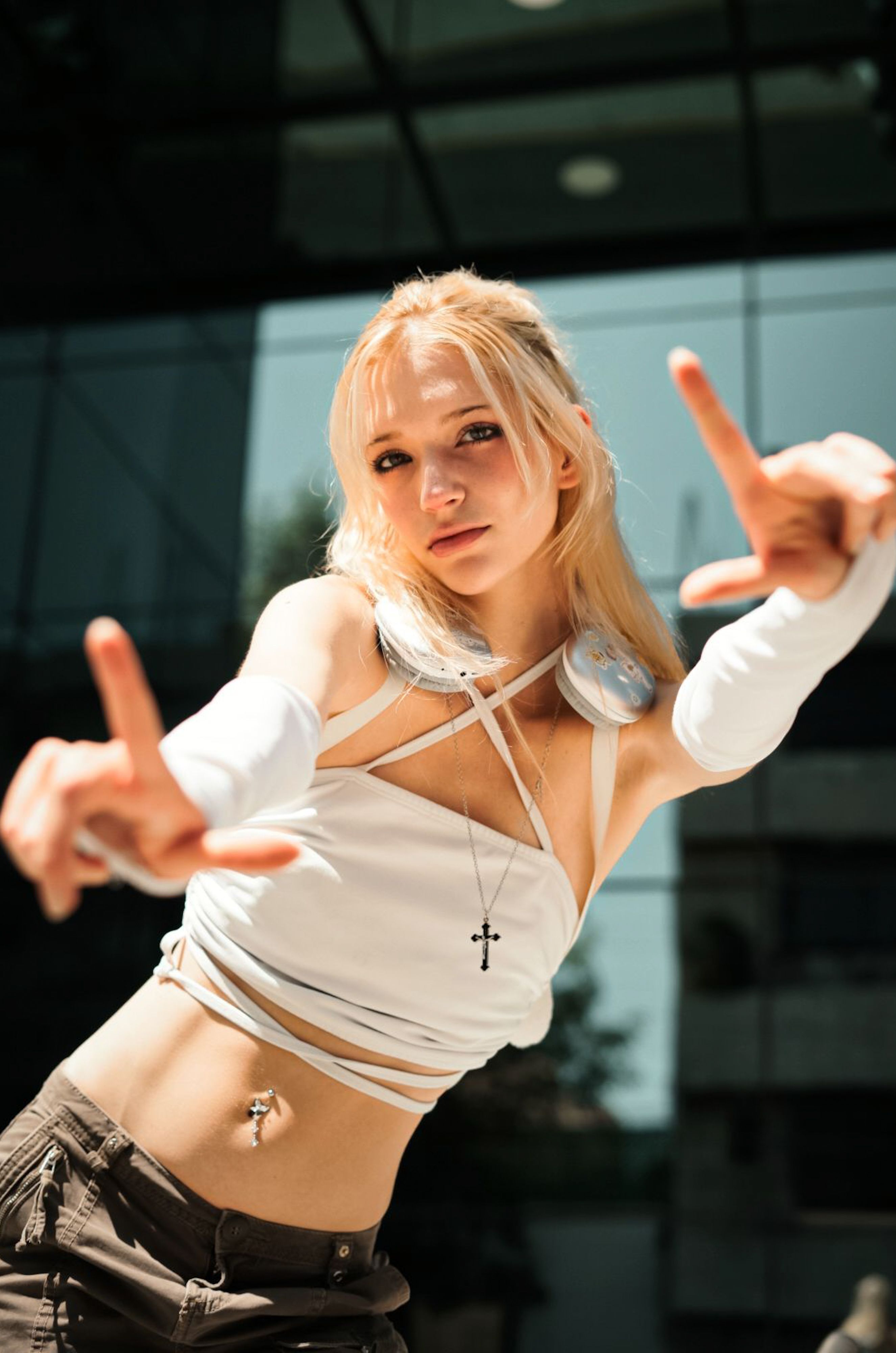 Fashionable young woman with headphones in urban environment, modeling a confident pose.
