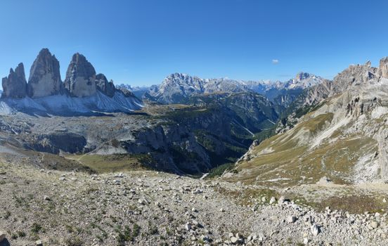 Panoramic view of the iconic Tre Cime di Lavaredo with clear blue skies in the Dolomites, Italy.