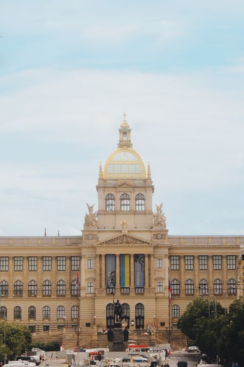 Free Front view of the iconic National Museum in Prague featuring a landmark dome and a statue with people gathered around. Stock Photo