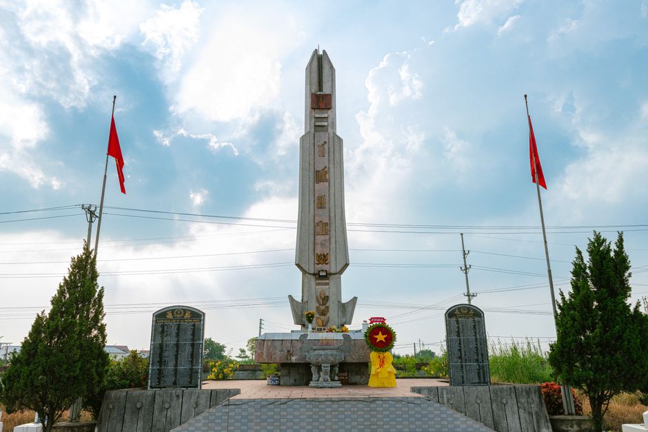 Historic Bach Dang victory memorial site in Quang Yen, Vietnam, stone monuments, traditional architecture, visitors walking quietly, summer sky, highly detailed documentary style