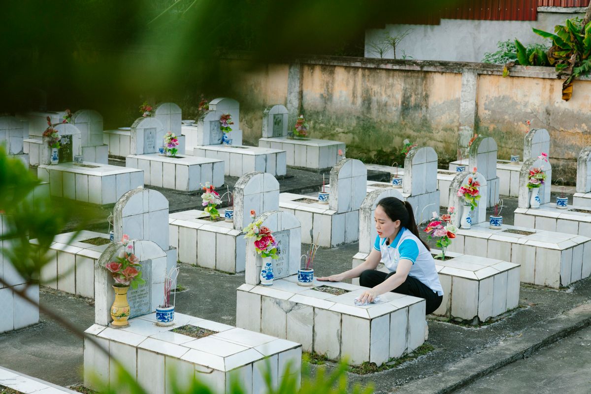 墓园中有人整理鲜花并进行祭拜，说明清明或忌日到福地祭拜时可准备鲜花、供品并保持环境整洁。