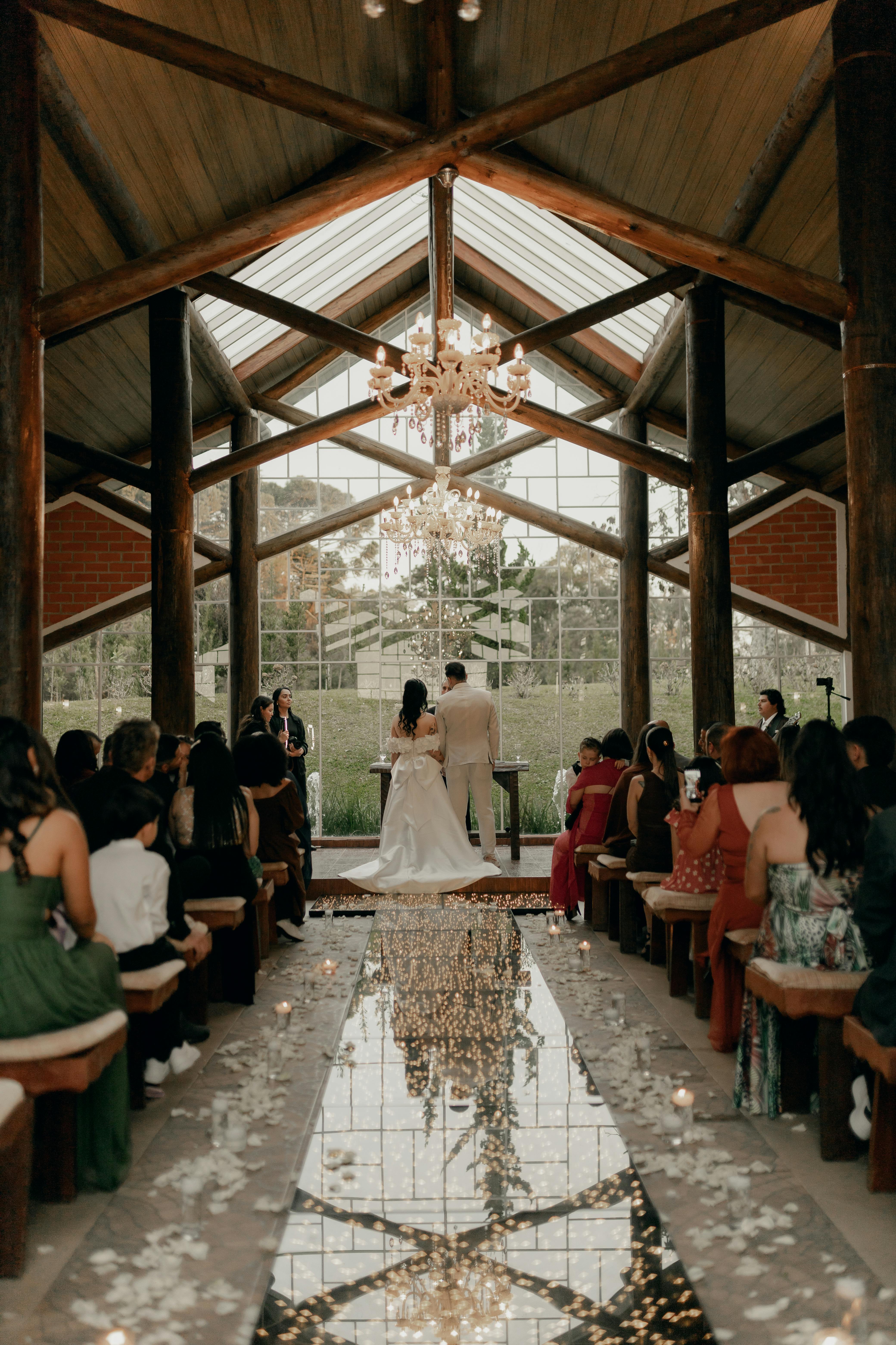 Beautiful indoor wedding ceremony with a bride and groom, lovely decor, and guests.