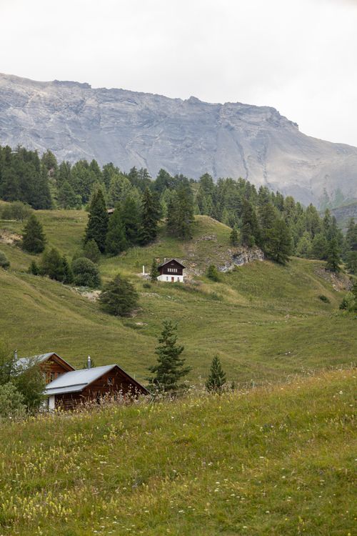 Free Idyllic Swiss mountain landscape in Valais with rolling hills and rustic cabins, perfect for nature lovers. Stock Photo