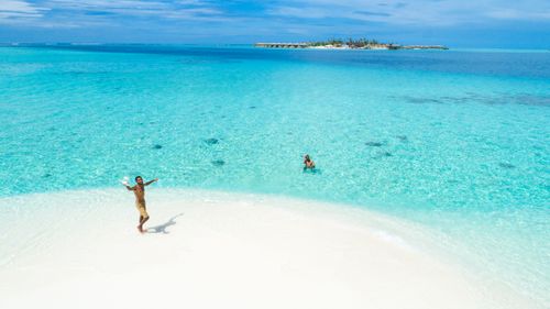 Free Aerial view of turquoise waters and white sandy beach with carefree people enjoying a tropical paradise. Stock Photo