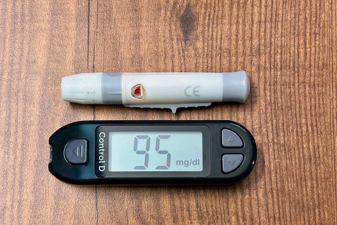 Glucometer displaying blood sugar reading alongside monitoring device