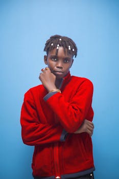 A striking portrait of a young person in a red jacket set against a blue backdrop. Modern style.