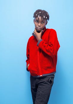 Fashion-forward adult wearing a red jacket against a vibrant blue backdrop.