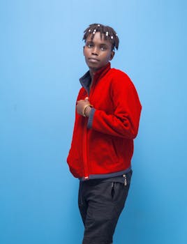 Young adult in red fleece jacket posing confidently, contrasting beautifully with a vivid blue backdrop.