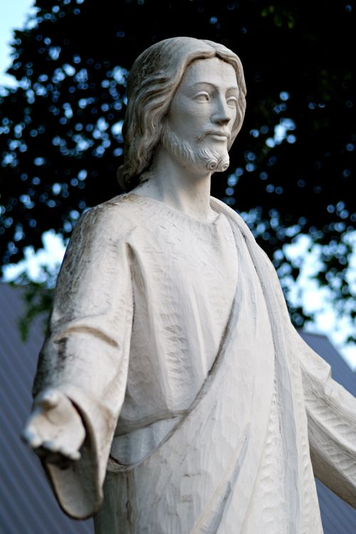 Free A close-up of a serene wooden Jesus statue under trees in South Miami. Stock Photo