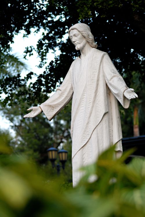 Free A peaceful statue of Christ surrounded by lush greenery in a South Miami park. Stock Photo