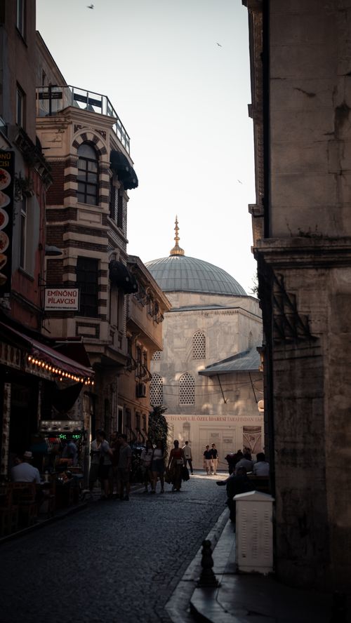 Free A scenic street view in Istanbul showcasing a historic dome, bustling with people and flanked by architectural buildings. Stock Photo