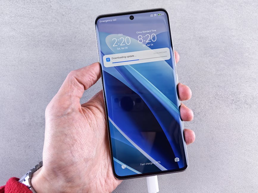 Close-up of a hand holding a smartphone with a downloading update notification on the screen.