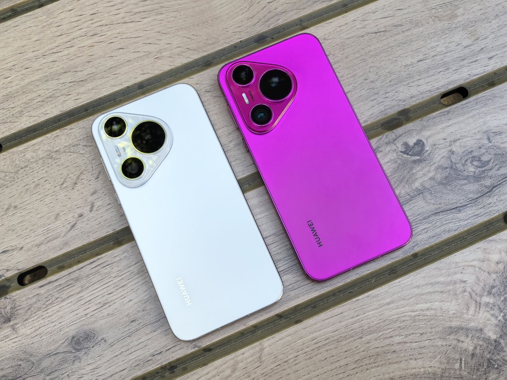 Two Huawei smartphones in white and pink on a wooden table with no people.