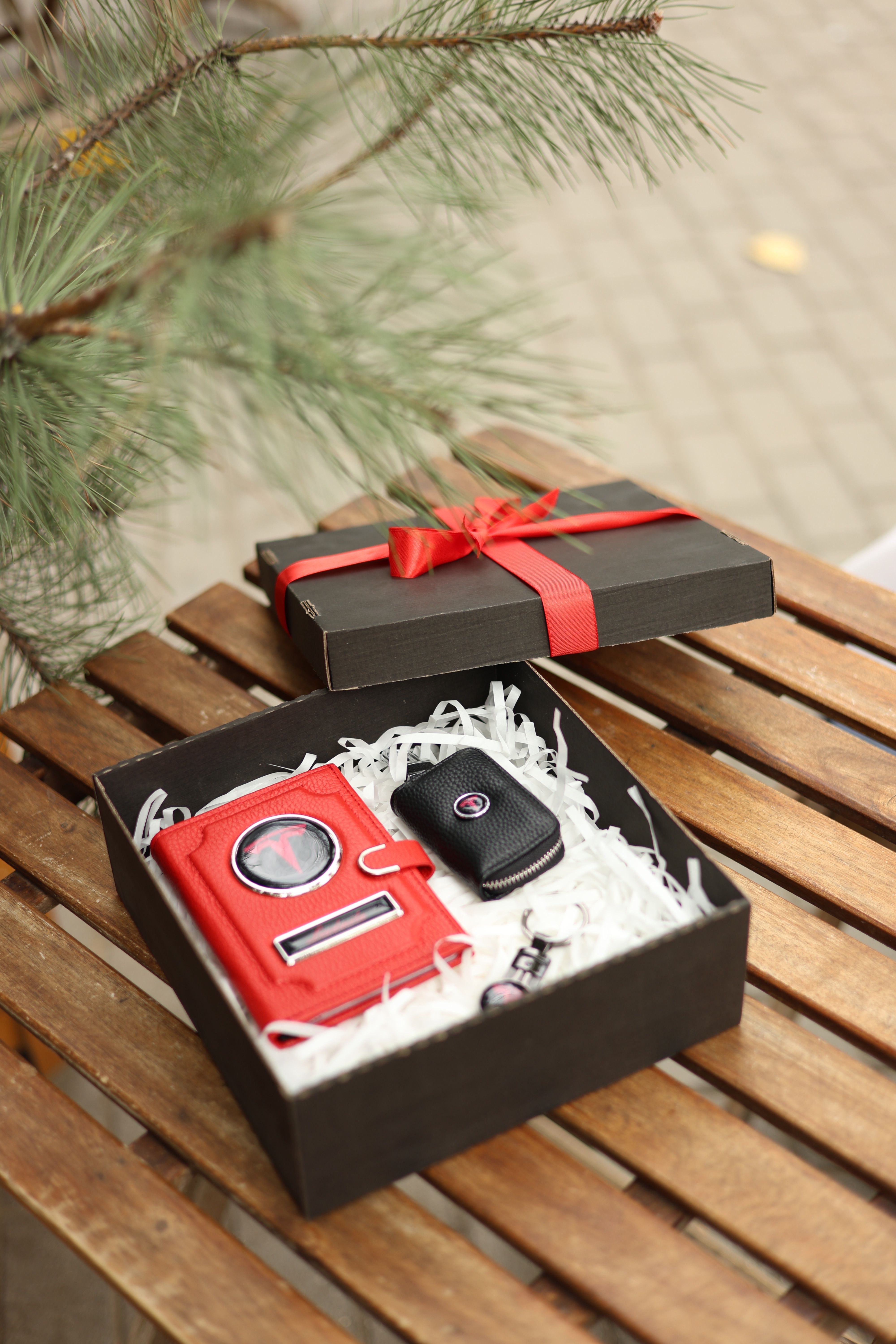 Elegant black gift box with a red key wallet on a wooden table, perfect for special occasions.