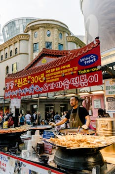 Bustling street food scene in Myeongdong, Seoul featuring a vendor selling traditional Korean dishes.