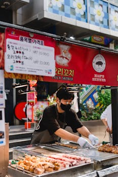 Street vendor grilling pork and duck skewers, showcasing dynamic urban street food culture.