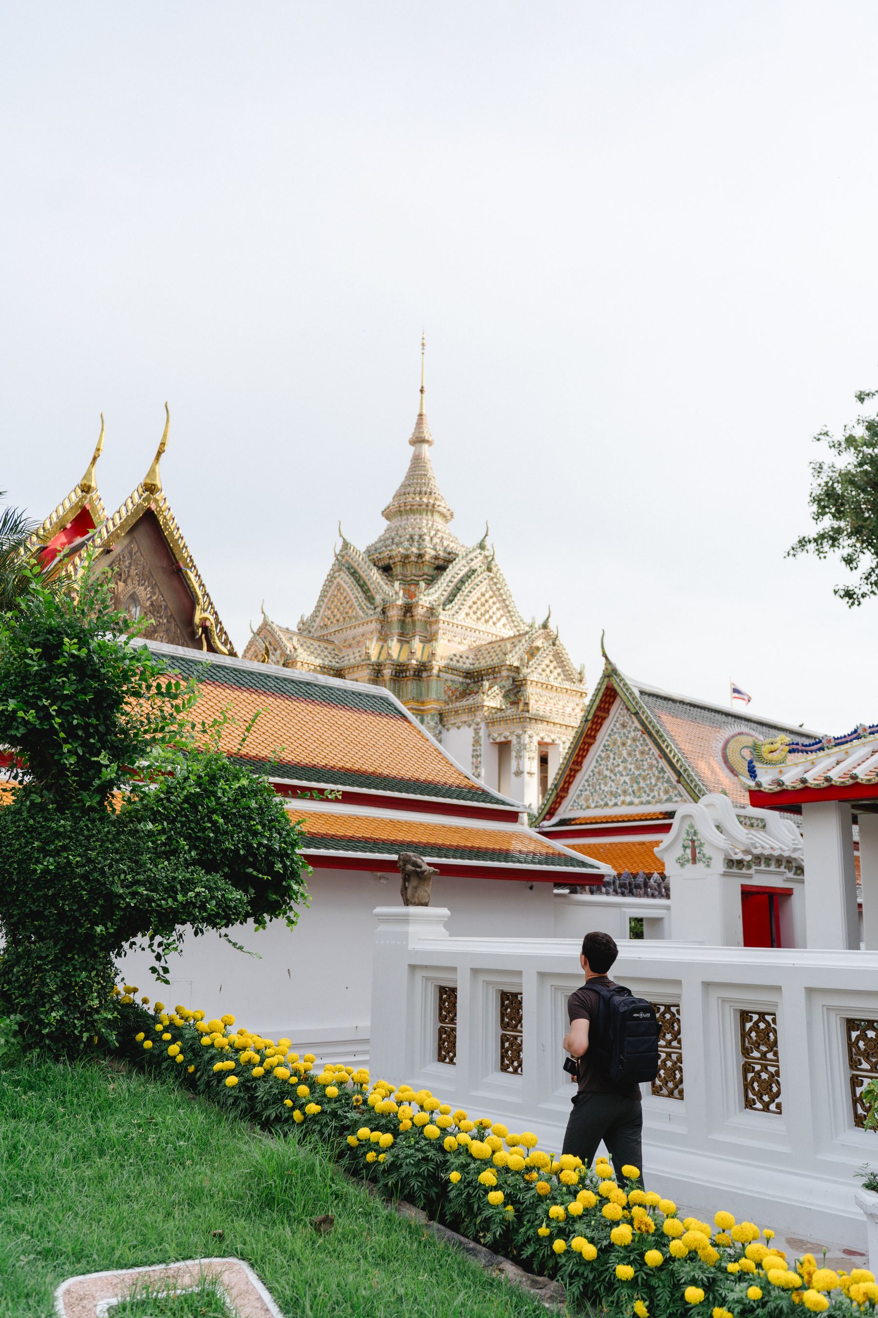 Traveler walking through Wat Pho among ornate roofs and golden spires