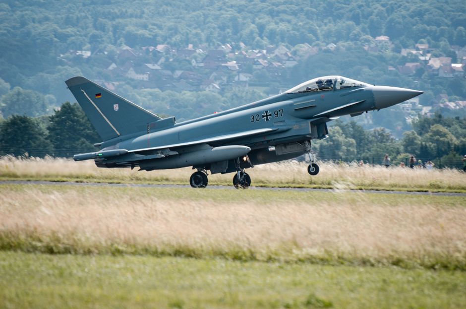 Eurofighter Typhoon jet taking off on a summer day with scenic hills in the background.