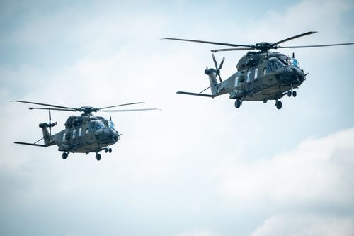 Free Two military helicopters flying in formation against a blue sky. Stock Photo