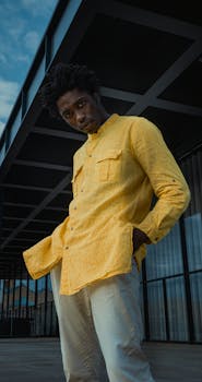 A fashionable man poses confidently in a bright yellow shirt, outdoors in Berlin.