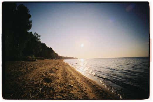 Peaceful sunrise over a tranquil beach with gentle waves and clear blue sky.