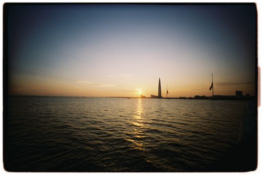Beautiful sunset view over water with a striking silhouette of a modern tower.