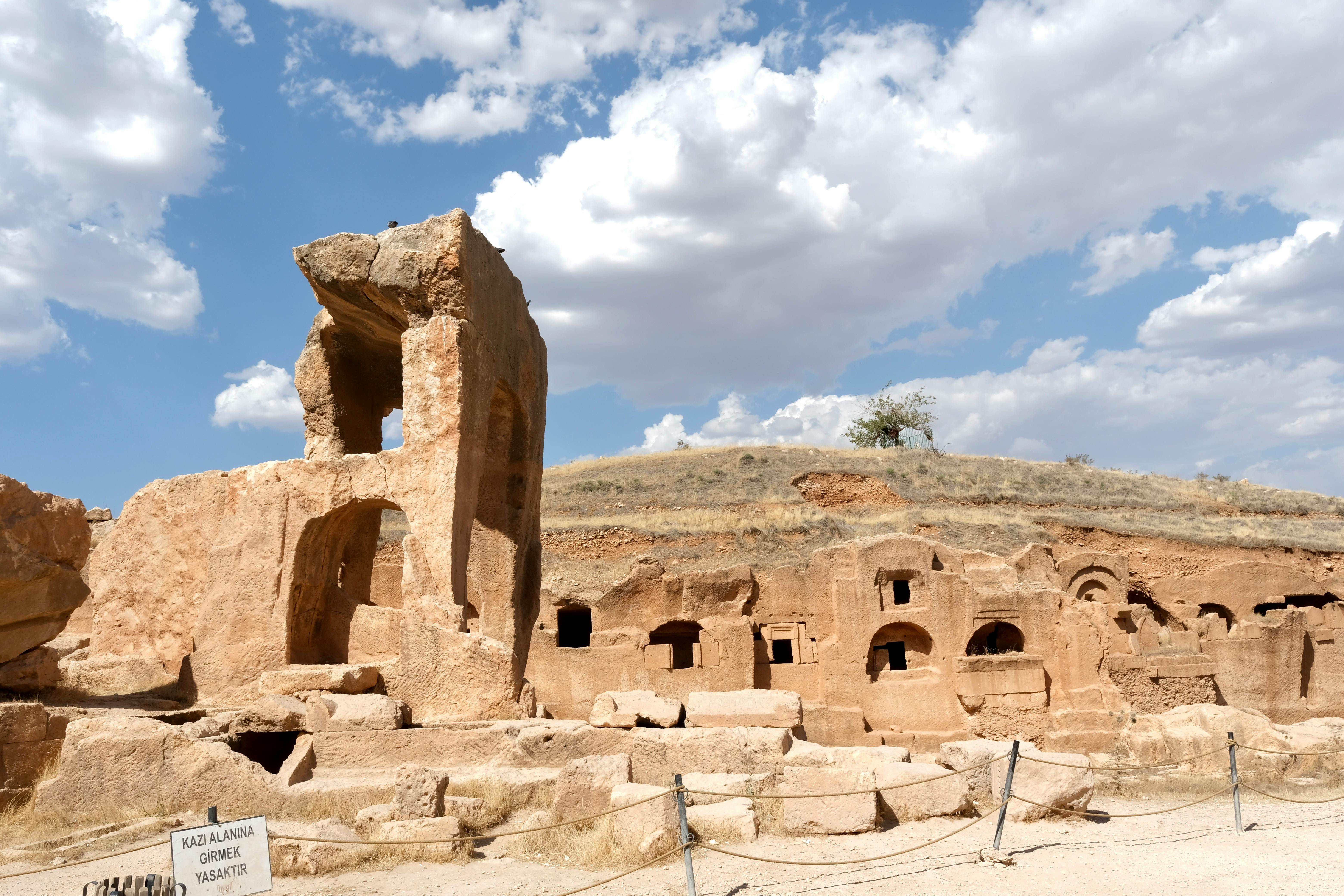 Explore ancient rock formations and caves under a bright sunny sky in Cappadocia, Turkey.