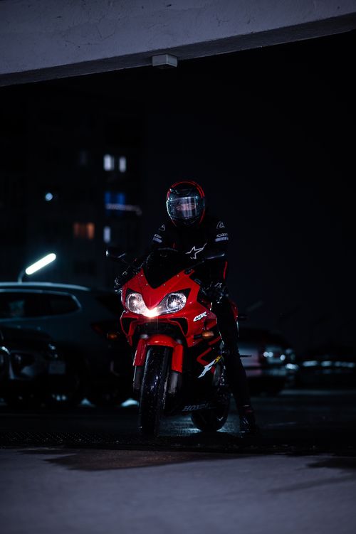 Free Biker in helmet rides red motorcycle at night in urban setting. Stock Photo