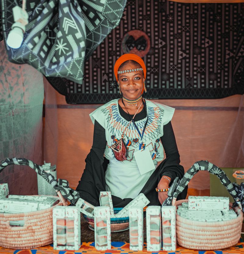 African artisan presenting handmade goods at her market stall