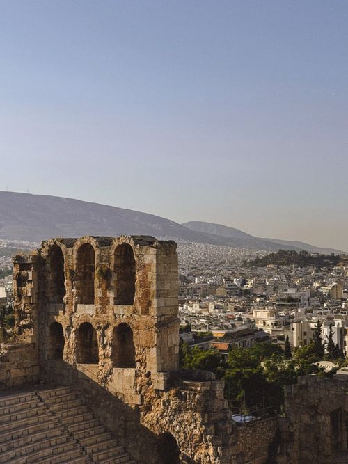 Free A scenic view of the ancient amphitheater in Athens, Greece, with a city skyline backdrop under a clear sky. Stock Photo