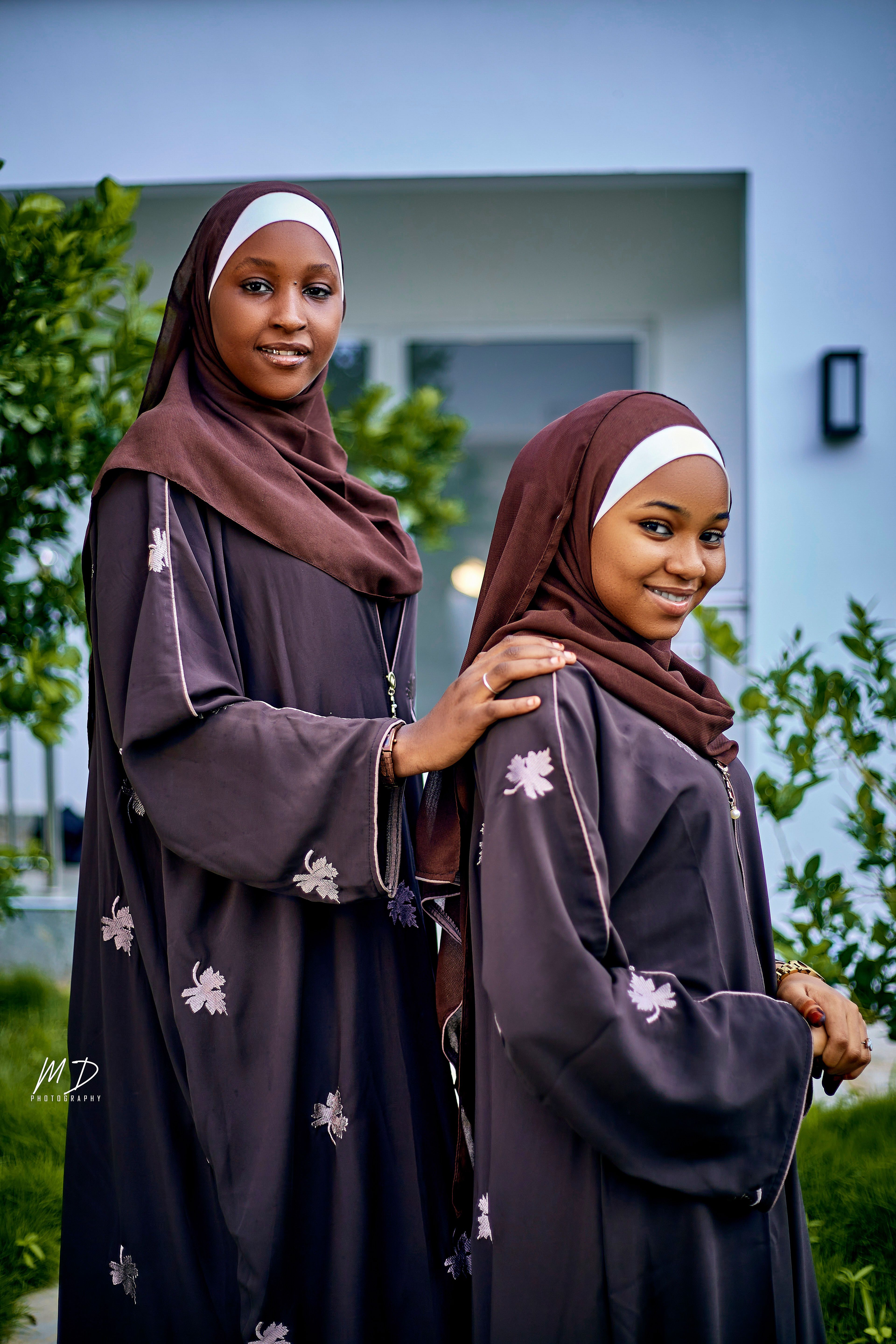 Two women in traditional attire sharing a moment outdoors. Smiling and relaxed.
