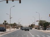 A street in Mauritania with cars and national flags under a clear sky.