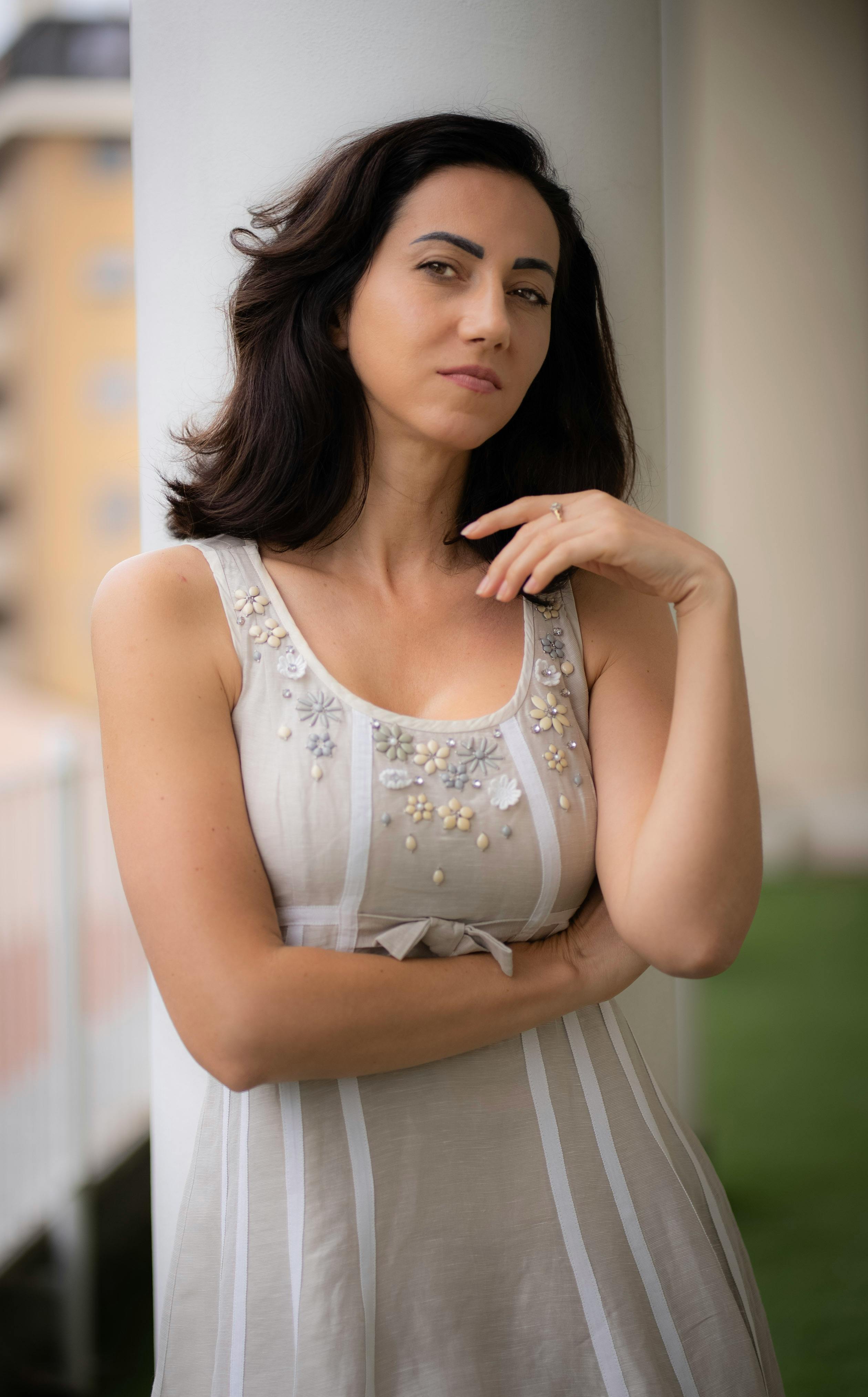 Elegant portrait of a woman in a floral dress leaning against a pillar in Milan, Italy.
