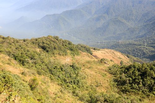 Free Breathtaking view of lush green hills and distant mountains under clear skies. Stock Photo