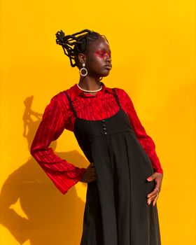 Striking portrait of a woman in red and black attire against a bold yellow background.
