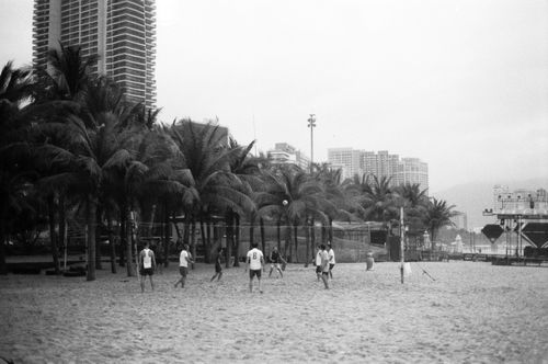 Free Beach volleyball game in black and white with urban buildings and palm trees in the background. Stock Photo