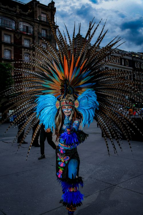 Free Vibrant traditional dancer with feathered headdress performing in a city square. Stock Photo