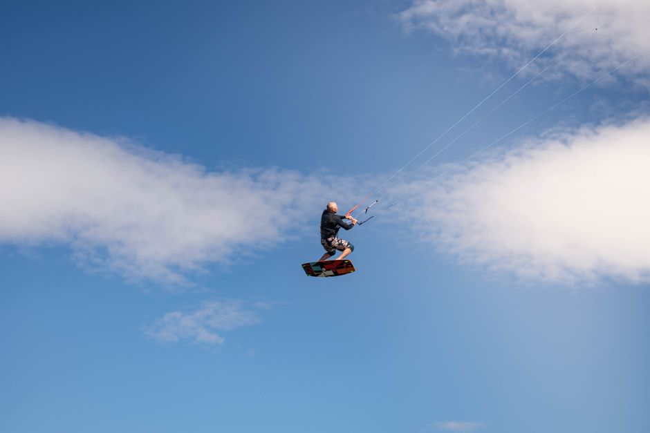 High-flying kiteboarder performing a stunt against a vibrant blue sky, capturing adventure and freedom.