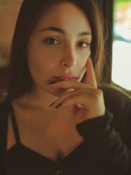 一位身着黑色上衣的年轻女子，在室内若有所思的特写肖像